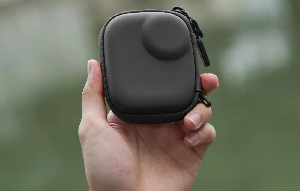 Dłoń trzymająca czarne etui Sunnylife na rozmytym tle