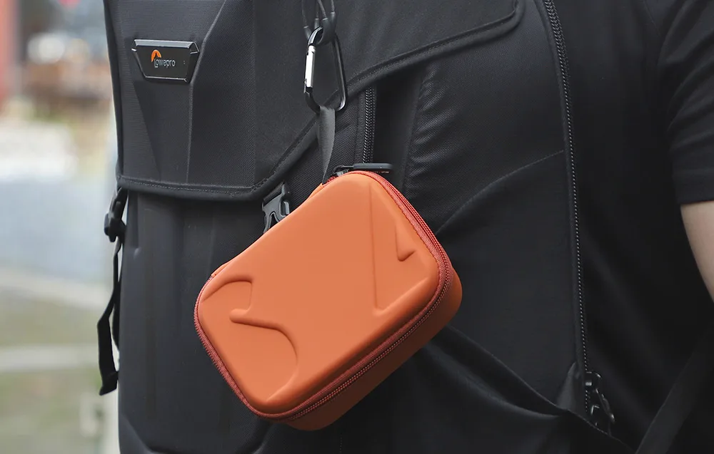 Pomarańczowe etui przypięte do plecaka przy pomocy karabińczyka