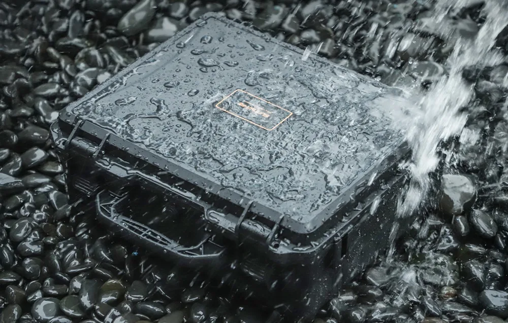 Closed Sunnylife protective case on rocks covered with water droplets during a splash test
