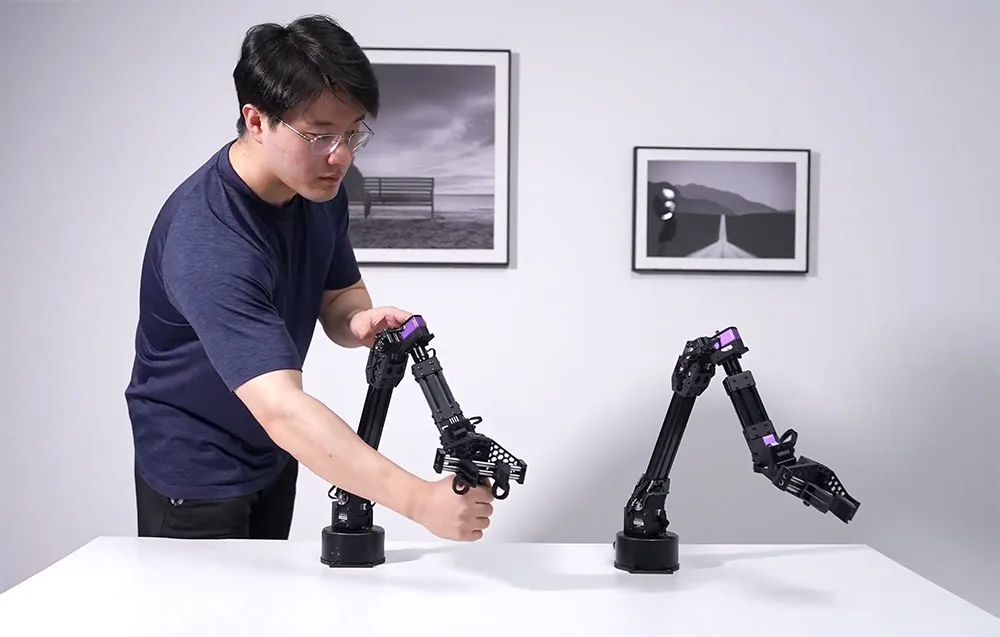 Man operating robotic arms placed on a white table