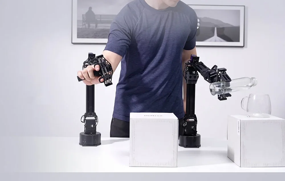 Man operating robotic arms, one of them pouring water into a cup