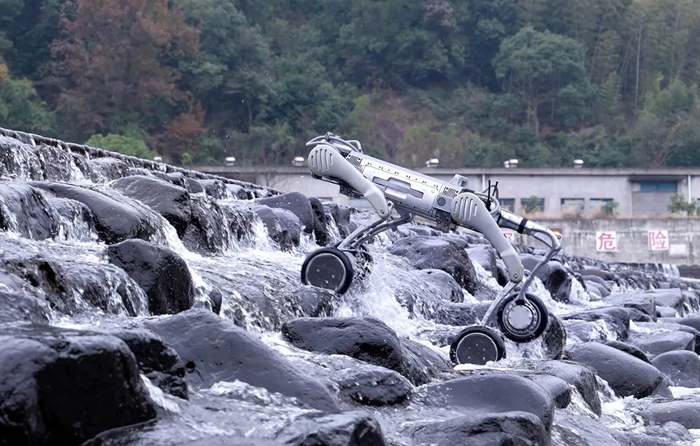 UNITREE B2-W wheeled quadruped robot climbing wet rocks in a mountain stream