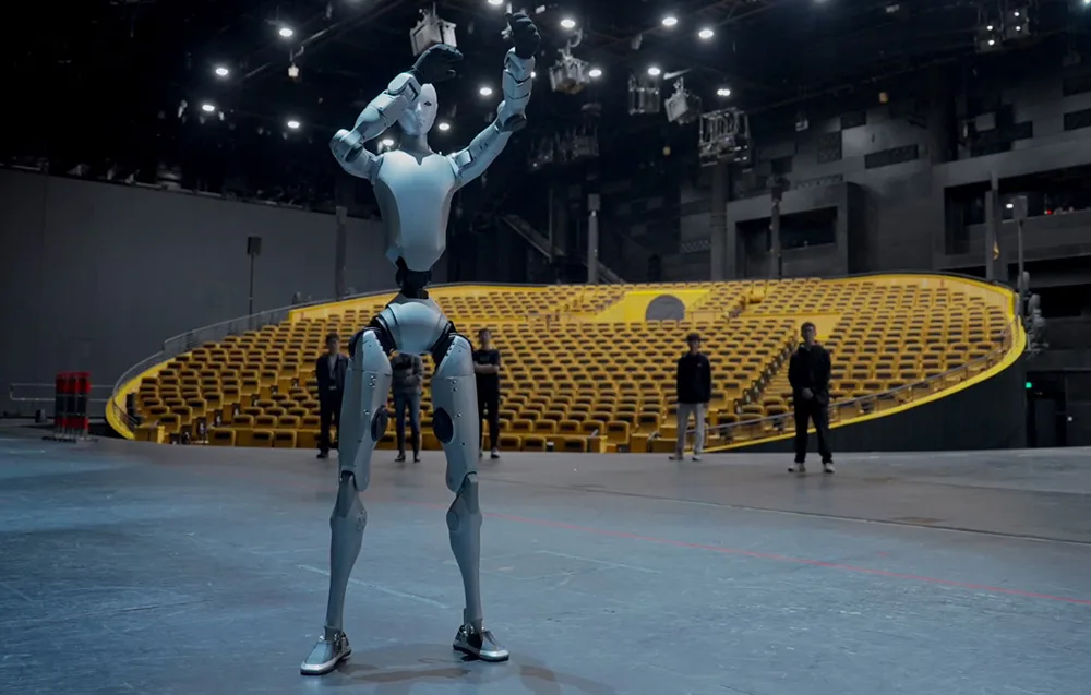UNITREE H2 Edu humanoid robot on a theater stage under spotlights facing an empty audience