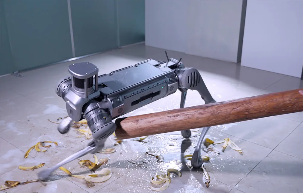 UNITREE B2 quadruped robot moving on a slippery floor with crushed bananas and approaching a wooden bar obstacle