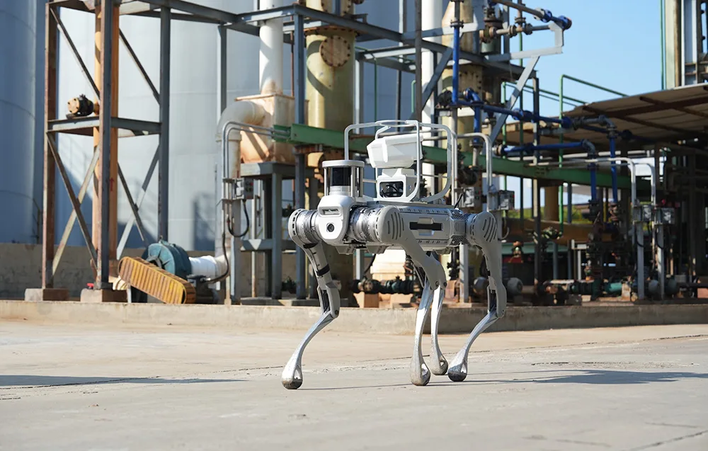 UNITREE B2 quadruped robot standing on a concrete surface in an industrial environment with pipes and tanks