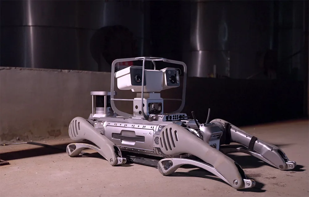 UNITREE B2 quadruped robot resting on the ground in a dim industrial environment