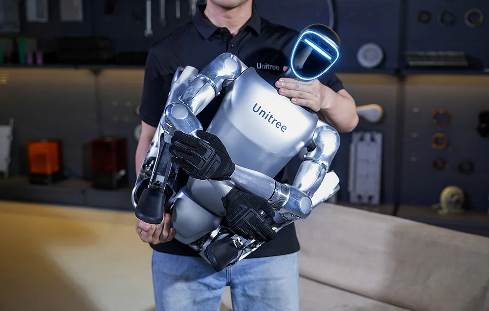 A person holding the UNITREE robot to showcase its compact design and mobility