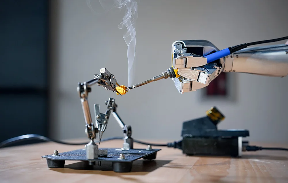 Robotic arm soldering small components using a soldering station
