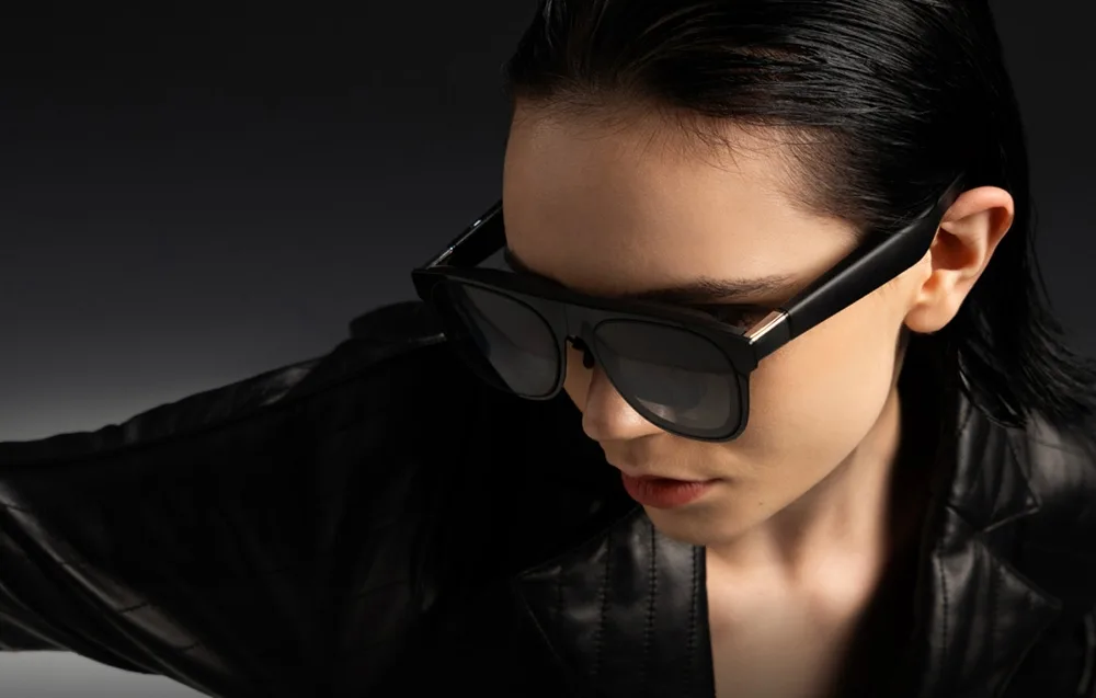 Темноволоса жінка в чорній куртці та AR-окулярах XREAL One Pro