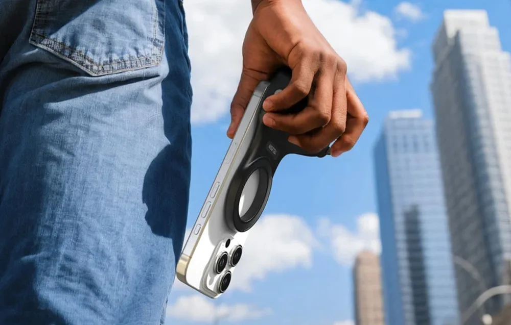 Hand holding a smartphone with the grip downward in front of tall buildings