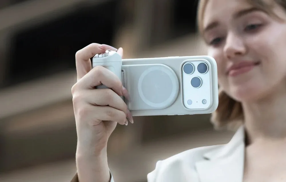 Woman holding a smartphone with the PGYTech MagCam 2 grip while taking a photo outdoors