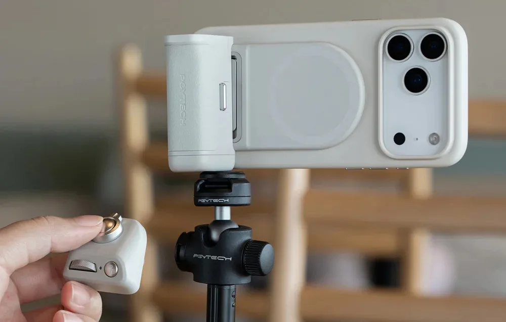 Smartphone mounted on a tripod with PGYTech MagCam 2 grip and Bluetooth remote in hand