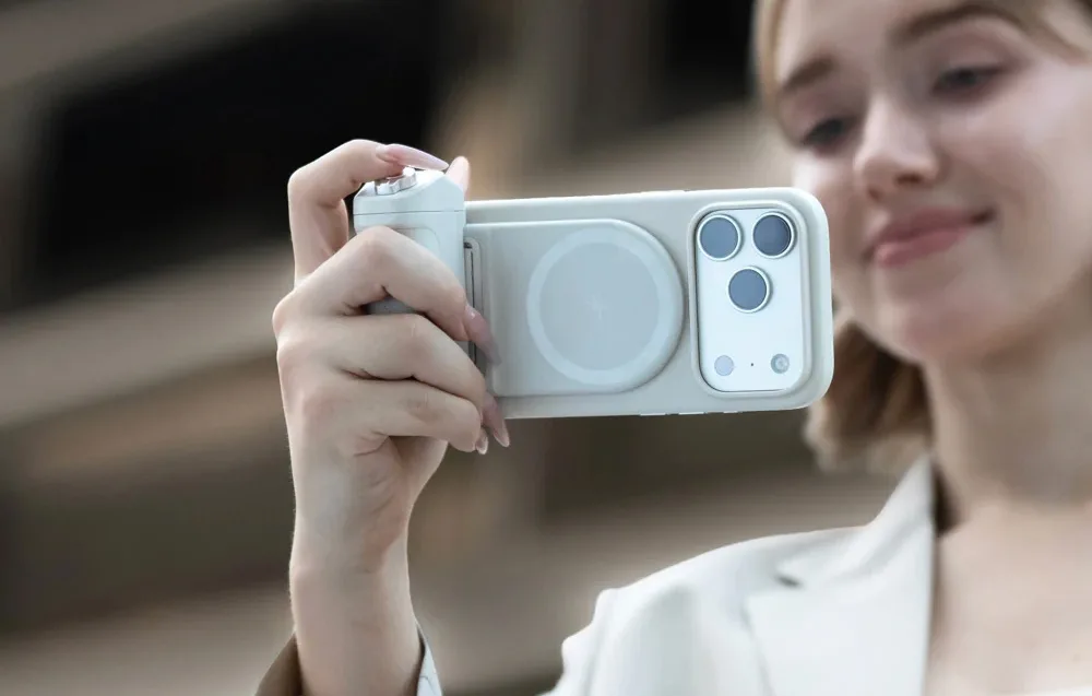 Woman holding a smartphone with PGYTech MagCam 2 grip while taking photos outdoors