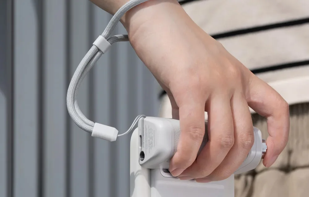 Hand holding the PGYTech MagCam 2 smartphone grip with wrist strap attached