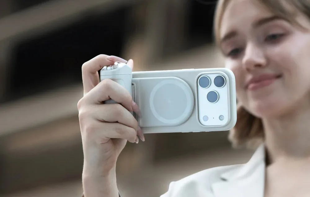 Woman holding a smartphone with the PGYTech MagCam 2 grip attached while taking a photo outdoors