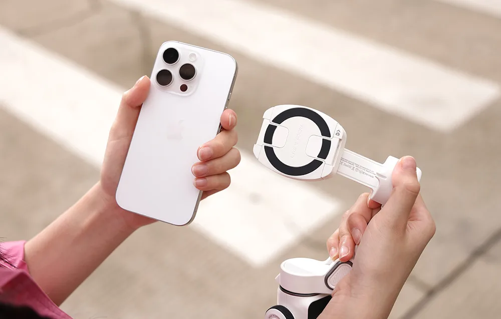 Dłoń trzyma iPhone’a oraz magnetyczny uchwyt montowany do gimbala, przygotowany do podłączenia.