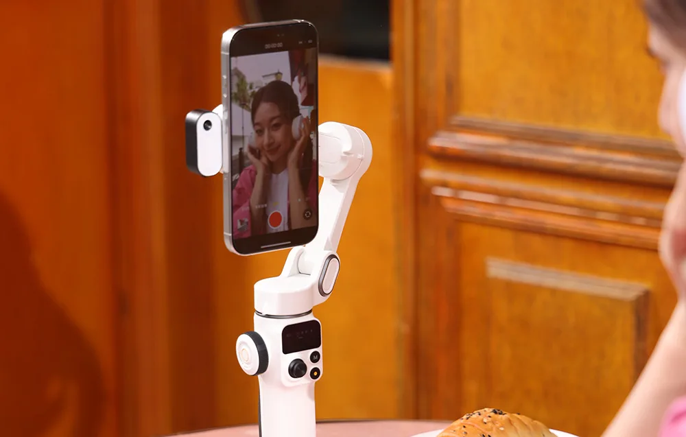 Smartfon zamocowany na gimbalu podczas nagrywania wideo w pomieszczeniu, widoczny podgląd na ekranie.