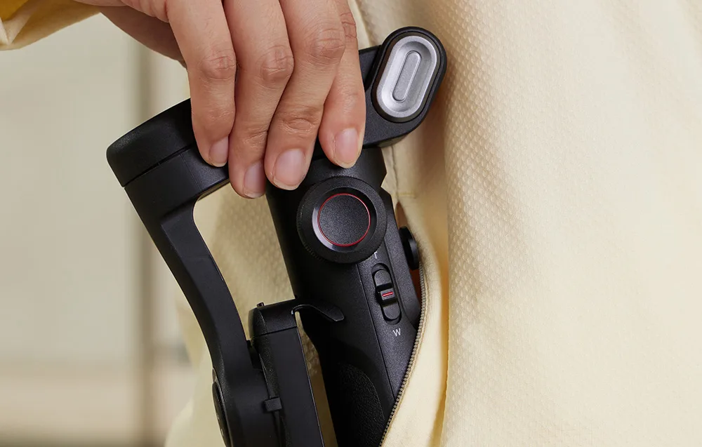 Dłoń wkłada składany kompaktowy gimbal do kieszeni bluzy,