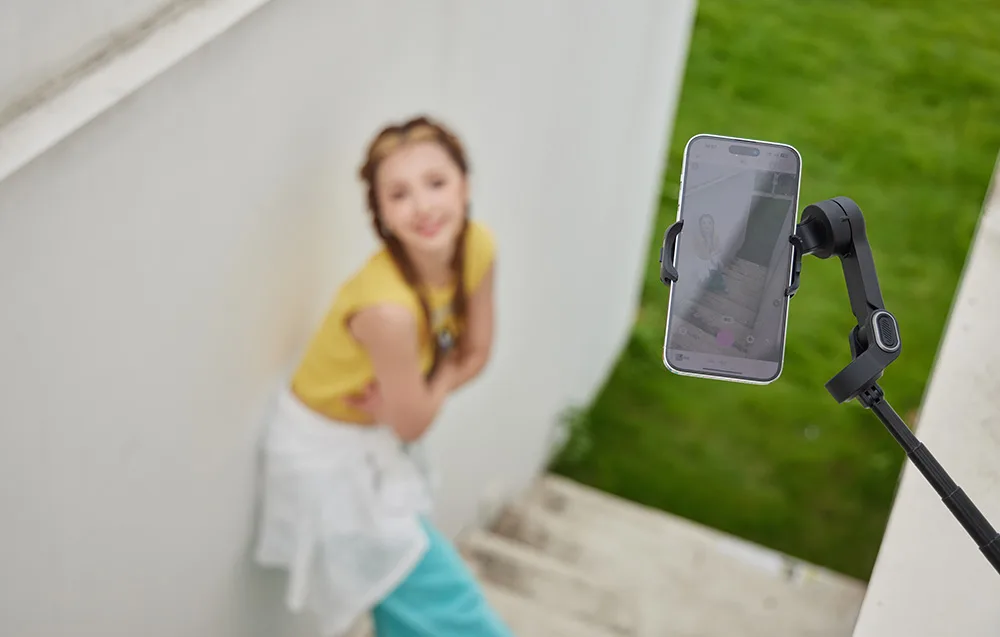 Gimbal nagrywający uśmiechniętą dziewczynę na schodach.