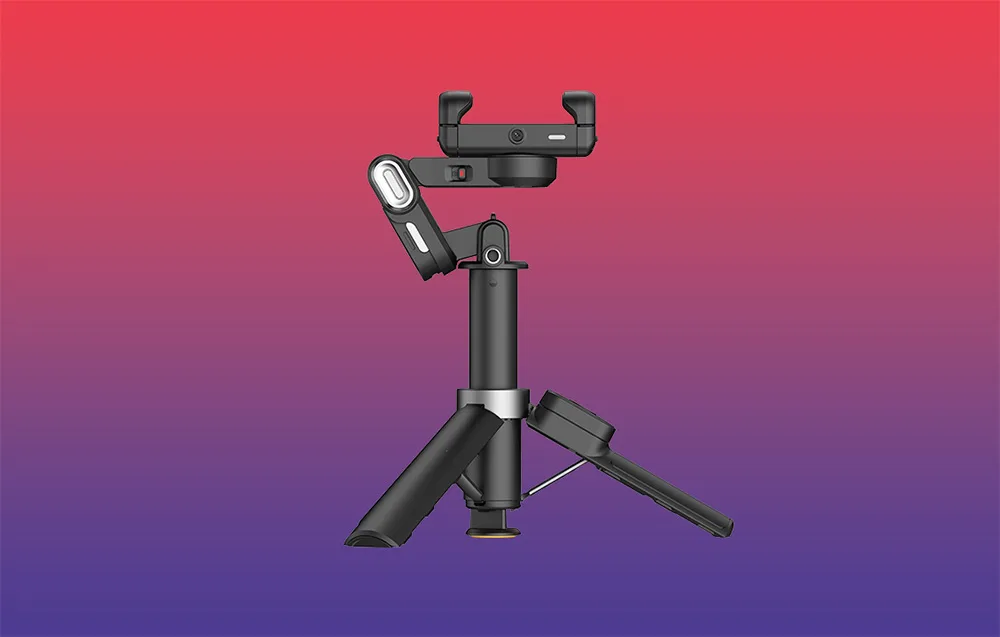 Gimbal ustawiony na mini statywie, widok z boku, na gradientowym tle czerwono-fioletowym.