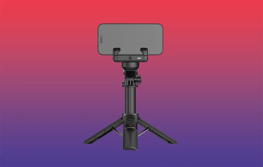Gimbal ze smartfonem w poziomie ustawiony na mini statywie, widok z tyłu, na gradientowym tle czerwono-fioletowym.