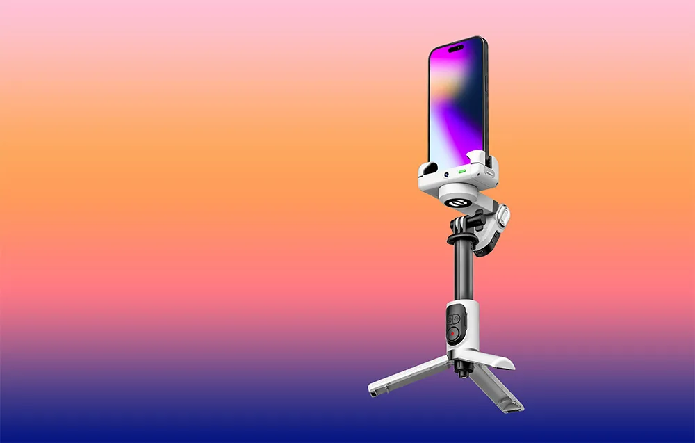 Gimbal ze smartfonem ustawiony na mini statywie na gradientowym tle pomarańczowo-fioletowym.