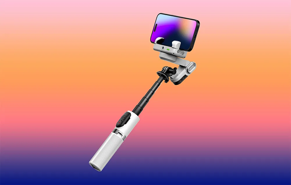 Gimbal ze smartfonem na wysuniętym wysięgniku na gradientowym tle w odcieniach pomarańczu i fioletu.