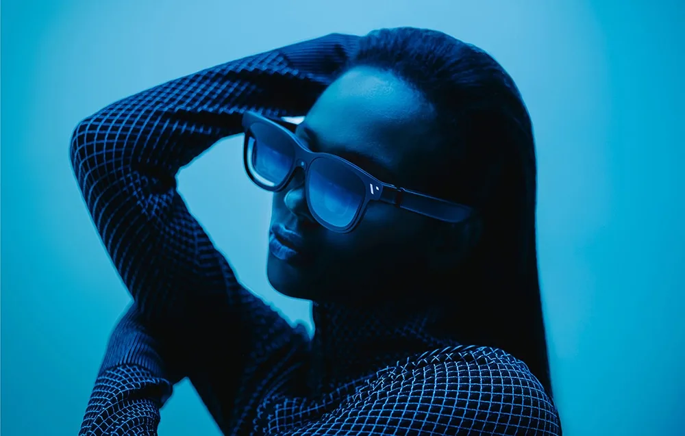 Woman wearing VITURE XR Beast glasses posing against a light blue background.