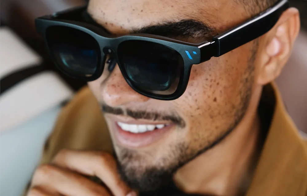 Close-up of a smiling man wearing VITURE XR Beast glasses with a blue symbol on the frame.