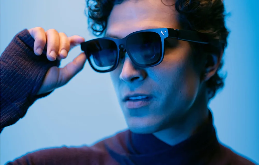 Close-up of a man wearing VITURE XR Beast glasses on a light blue background.