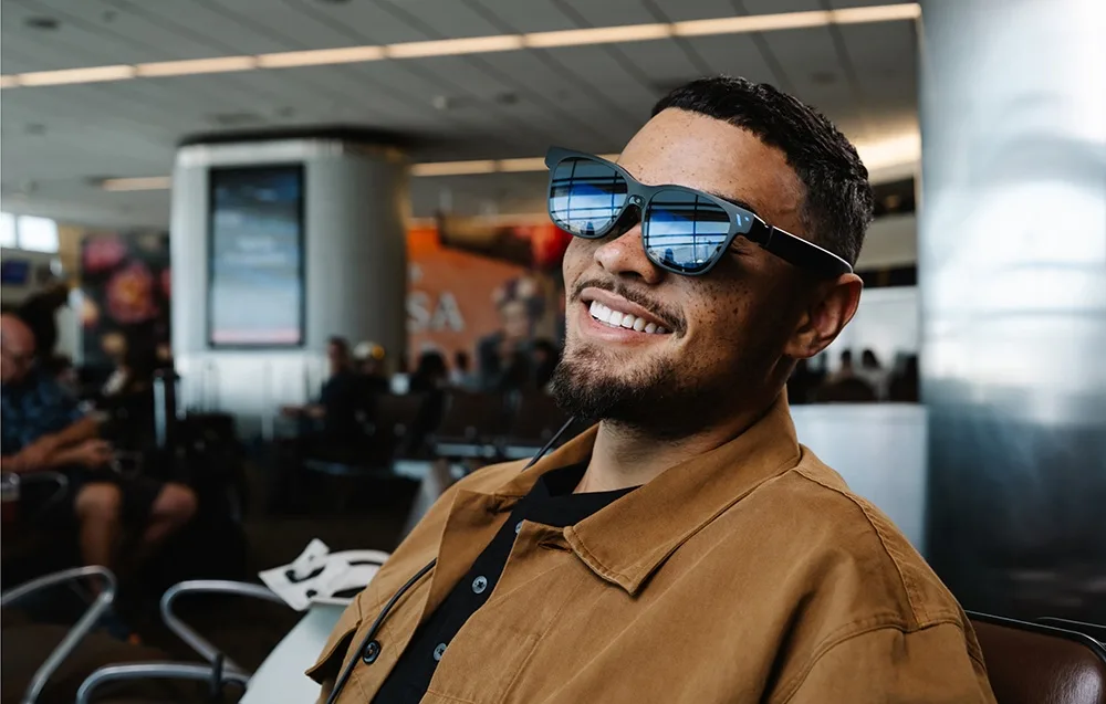 Smiling man wearing VITURE XR Beast glasses in a bright modern interior.