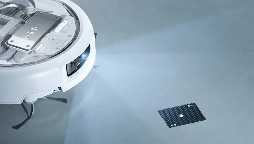 DJI Romo robot vacuum with illuminated camera aimed at a calibration marker on the floor