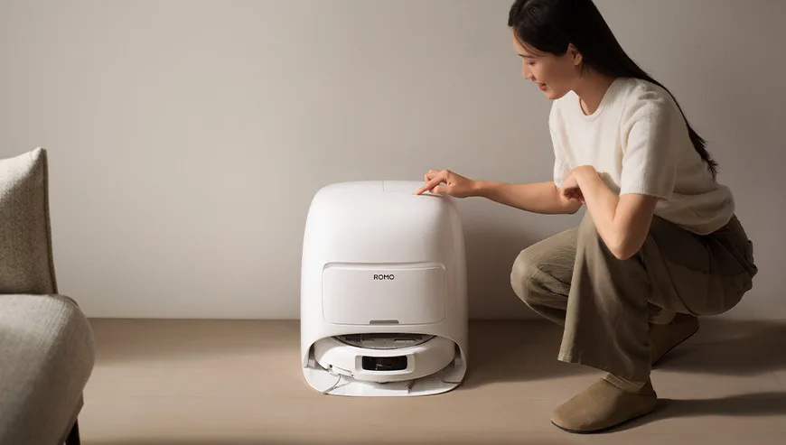 Woman kneeling next to the DJI Romo docking station and pressing a button on the top panel