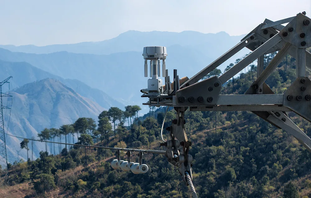 Stacja naziemna DJI zamontowana na metalowej konstrukcji technicznej, na tle zalesionych gór