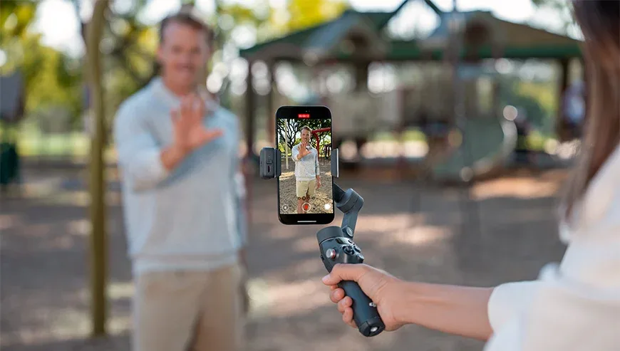 Kobieta nagrywająca mężczyznę na dworze za pomocą smartfona na gimbalu DJI Osmo Mobile 8