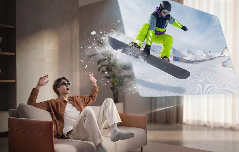 Mężczyzna w okularach AR siedzi na kanapie, po prawej wyświetlony obraz osoby na desce snowboardowej